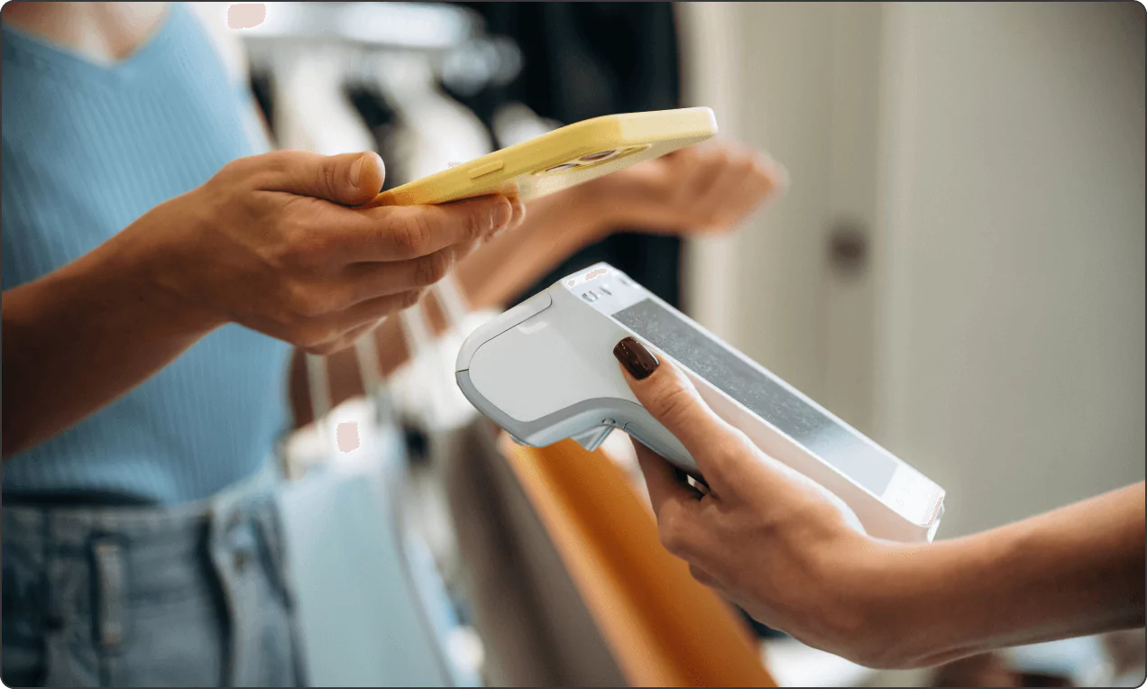 Customer taps smartphone for contactless payment on handheld POS held by staff.