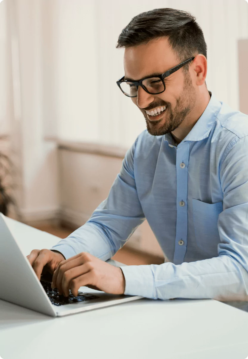 A smiling man using a laptop.